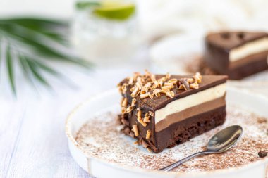 Tatil pastası. Üç çikolata. İki beyaz tabakta iki porsiyon var. Hafif bir arkaplanda. Doğum günü, tatiller, şekerler. Boşluğu kopyala