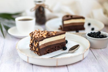 Tatil pastası. Üç çikolata. İki beyaz tabakta iki porsiyon var. Hafif bir arkaplanda. Doğum günü, tatiller, şekerler. Boşluğu kopyala