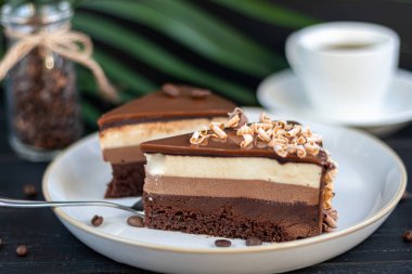 Tatil pastası. Üç çikolata. İki tabak, iki porsiyon. Siyah bir arka planda. Doğum günü, tatiller, şekerler. Boşluğu kopyala