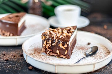 Tatil pastası. Üç çikolata. İki tabak, iki porsiyon. Siyah bir arka planda. Doğum günü, tatiller, şekerler. Boşluğu kopyala