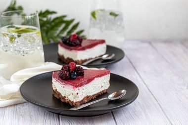 İki beyaz tabakta cheesecake, iki porsiyon. Taze böğürtlenlerle süslenmiş beyaz bir arka planda. Doğum günü, tatiller, şekerler. Yakınlarda içerim. Boşluğu kopyala