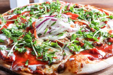 Domuz pastırmalı pizza ve ahşap bir tabakta peynir ve domates soslu otlar. Karanlık bir arka planda. Boşluğu kopyala