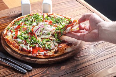 Domuz pastırmalı pizza ve ahşap bir tabakta peynir ve domates soslu otlar. Karanlık bir arka planda. Boşluğu kopyala