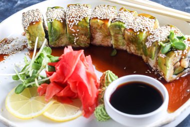 Philadelphia peyniri, avokado ve somonla yuvarlanıyor. Mikroyeşille sos ve garnitür koy. Karanlık bir arka planda. Boşluğu kopyala