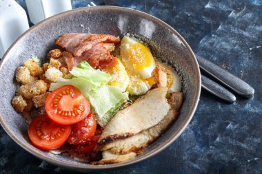 Izgara tavuklu Sezar salatası, domates, marul, kraker ve yumurta. Sağlıklı beslenme. Karanlık bir arka planda. Boşluğu kopyala.