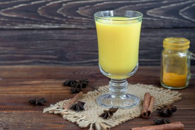 Masala çayı ya da kışın bağışıklığı arttırmak için kullanışlı süt ve baharatlı geleneksel Hint içeceği. Ahşap bir arka planda. Boşluğu kopyala