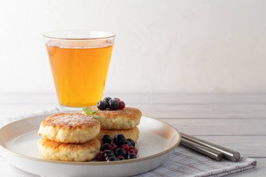 Beyaz bir fenerin üzerinde süzme peynirli ev yapımı krep, siyah frenk üzümü ve kızılcık. Tüm aile için bir kahvaltı. Sağlıklı vejetaryen gıda konsepti. Boşluğu kopyala.