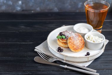 Koyu bir fenerin üzerinde süzme peynirli ev yapımı krep, siyah frenk üzümü ve kızılcık. Tüm aile için bir kahvaltı. Sağlıklı vejetaryen gıda konsepti. Boşluğu kopyala.