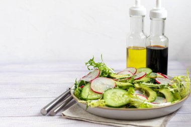 Taze salatalık, ıspanak yaprağı, roka, avokado. Dilimlenmiş yumurta ve kırmızı biberle servis ediliyor. Beslenme düzeni. Tüm aile için bir kahvaltı. Vitamin tabağı. Hafif bir arkaplanda. Boşluğu kopyala