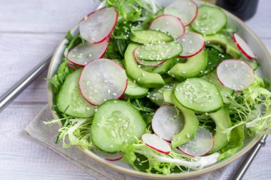 Taze salatalık, ıspanak yaprağı, roka, avokado. Dilimlenmiş yumurta ve kırmızı biberle servis ediliyor. Beslenme düzeni. Tüm aile için bir kahvaltı. Vitamin tabağı. Hafif bir arkaplanda. Boşluğu kopyala