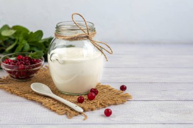 Seramik kaşıkla ahşap arka planda cam kavanozda ev yapımı yoğurt. Sağlıklı diyet yemekleri. Vejetaryen yemeği. Boşluğu kopyala