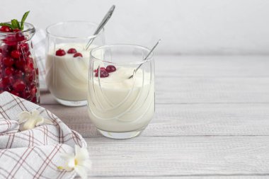 Hafif ahşap arka planda iki bardak ev yapımı yoğurt. Naneli ve böğürtlenli. Sağlıklı diyet yemekleri. Vejetaryen yemeği. Boşluğu kopyala