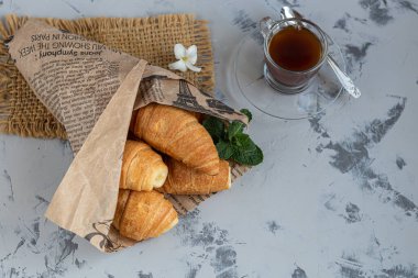 Kahvaltıda kruvasan ve kahve, arka planda taze ahududu reçeli. Bir tutam nane ile süslenmiş. Boşluğu kopyala.