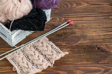 El yapımı. Ahşap bir arka planda metal örgü iğneleri ve yün iplikler. Evde süveter örüyorum. Hobi.