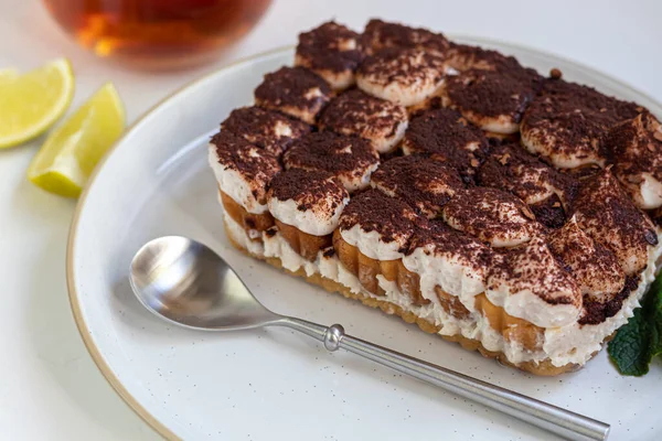 Tiramisu. Betonun altında beyaz arka planda geleneksel İtalyan tatlıları. Nane filizi ve limon dilimleriyle süslenmiş. Şeffaf bir fincan çayın içinde. Boşluğu kopyala