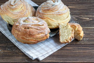 Kuru üzüm ve kuru meyveli fırın ürünleri koyu ahşap arka planda yer almaktadır. Üzerine krema serpilmiş şeker. Kraffinler. Paskalya yemeği. Boşluğu kopyala
