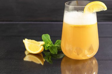 Taze ev yapımı zencefilli bira kokteyli. Masada buz ve limon var. Siyah bir arka planda. Boşluğu kopyala