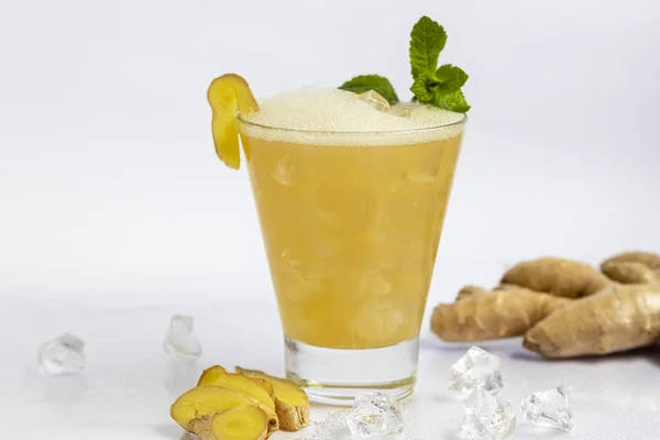 Taze ev yapımı zencefilli bira kokteyli. Masada buz ve limon var. Beyaz arka planda. Boşluğu kopyala.