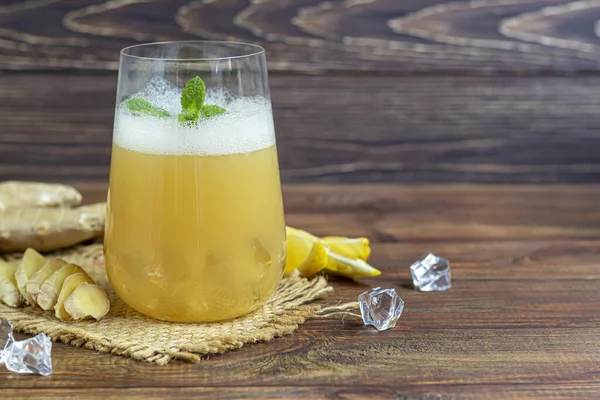 Taze ev yapımı zencefilli bira kokteyli. Masada buz ve limon var. Siyah bir arka planda. Boşluğu kopyala