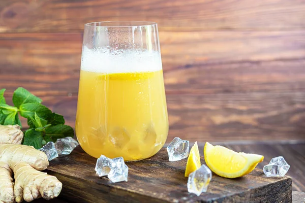 Taze ev yapımı zencefilli bira kokteyli. Masada buz ve limon var. Siyah bir arka planda. Boşluğu kopyala