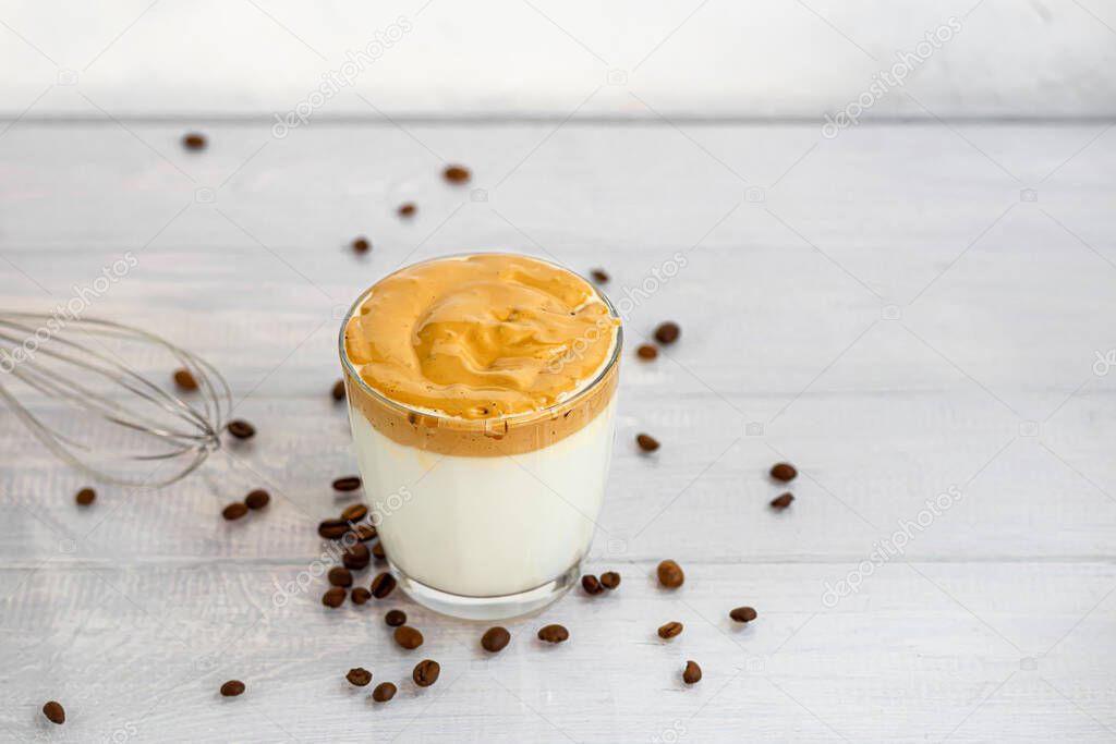 Dalgona coffee is a trendy cold Korean drink. Tasty, aromatic coffee with milk and sugar in a glass on a white background. Copy space