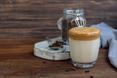 Dalgona kahvesi soğuk Kore içeceğidir. Lezzetli, aromatik kahve. Sütlü ve şekerli. Ahşap bir arka planda. Boşluğu kopyala