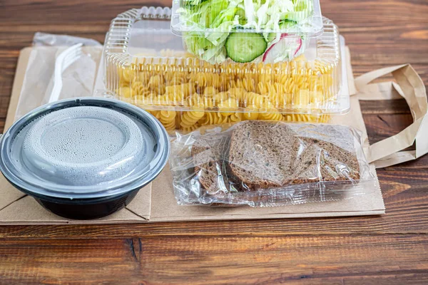 Karantina sırasında bir parti için yiyecek teslimatı. Fast food. Kurye paket servisi yapar. Karantina koşulları altında teslimat, salgın hastalıklar, Coronavirus covid-19 salgını. Ahşap bir arka planda. Boşluğu kopyala.