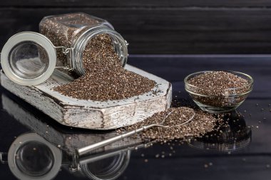 Cam kaplamalı siyah chia tohumları sağlıklı vitamin ve mineraller içerir. Metal kaşıkla siyah bir arka planda. Boşluğu kopyala