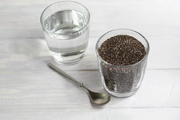 黑色的奇亚种子在一个玻璃碗里 水浸透了 在白色的背景上用金属勺子 复制空间 — 图库照片