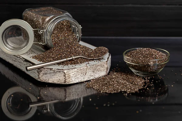 Cam kaplamalı siyah chia tohumları sağlıklı vitamin ve mineraller içerir. Metal kaşıkla siyah bir arka planda. Boşluğu kopyala
