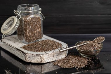 Cam kaplamalı siyah chia tohumları sağlıklı vitamin ve mineraller içerir. Metal kaşıkla siyah bir arka planda. Boşluğu kopyala
