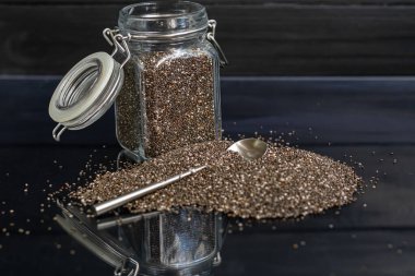 Cam kaplamalı siyah chia tohumları sağlıklı vitamin ve mineraller içerir. Metal kaşıkla siyah bir arka planda. Boşluğu kopyala