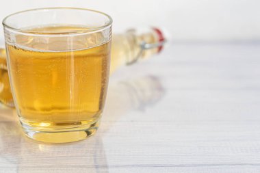 Sağlıklı organik gıdalar. Cam kasede elma şarabı ve arka planda taze kırmızı elmalar. Bir bardak buz ve yakınlardaki tarçın çubuklarıyla. Boşluğu kopyala