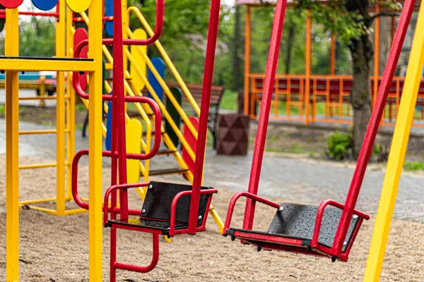 Yağmurda çocuk parkında boş salıncak. Parkta çocuk salıncağı, ahşap banklar, slaytlar, spor malzemeleri. Boş şehir, karantina. Yalnızlık kavramı.