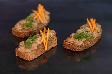 Havuç, soğan ve tereyağlı taze ev yapımı tavuk ciğeri ezmesi. Dereotu filizi ile süslenmiş. Ekmekle kayganlaştırılmış. Siyah bir arka planda. Boşluğu kopyala