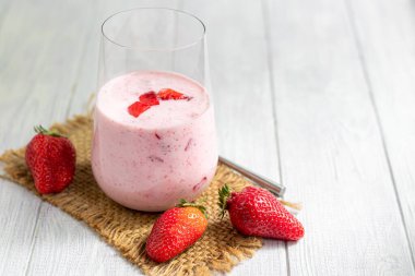 Beyaz arka planda çilekli ve yoğurtlu smoothie. Mürver çiçekleri ve çileklerle süslenmiş. Sağlıklı beslenme, diyet. Boşluğu kopyala.