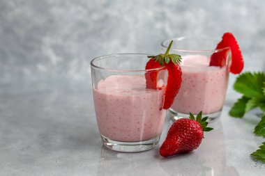 Gri arka planda çilekli ve yoğurtlu smoothie. Mürver çiçekleri ve çileklerle süslenmiş. Sağlıklı beslenme, diyet. Boşluğu kopyala.