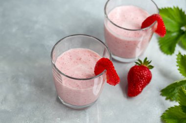 Gri arka planda çilekli ve yoğurtlu smoothie. Mürver çiçekleri ve çileklerle süslenmiş. Sağlıklı beslenme, diyet. Boşluğu kopyala.