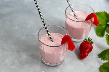 Gri arka planda çilekli ve yoğurtlu smoothie. Mürver çiçekleri ve çileklerle süslenmiş. Sağlıklı beslenme, diyet. Boşluğu kopyala.
