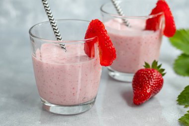 Gri arka planda çilekli ve yoğurtlu smoothie. Mürver çiçekleri ve çileklerle süslenmiş. Sağlıklı beslenme, diyet. Boşluğu kopyala.