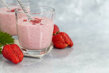 Gri arka planda çilekli ve yoğurtlu smoothie. Mürver çiçekleri ve çileklerle süslenmiş. Sağlıklı beslenme, diyet. Boşluğu kopyala.