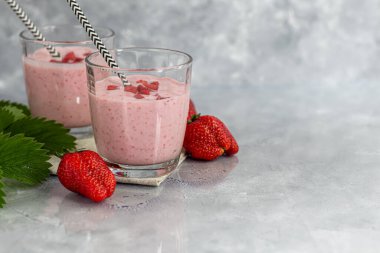Gri arka planda çilekli ve yoğurtlu smoothie. Mürver çiçekleri ve çileklerle süslenmiş. Sağlıklı beslenme, diyet. Boşluğu kopyala.