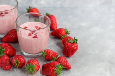 Gri arka planda çilekli ve yoğurtlu smoothie. Mürver çiçekleri ve çileklerle süslenmiş. Sağlıklı beslenme, diyet. Boşluğu kopyala.
