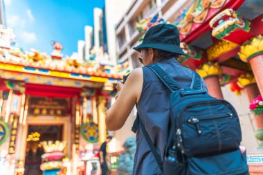 Traveler woman with backpack looking and taking photo Chinese sh