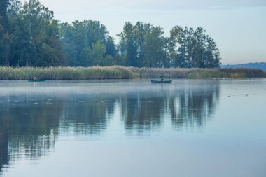 Tekneler, doğa ve göl ile Fishermens. Sis ve büyük ağaçlar.