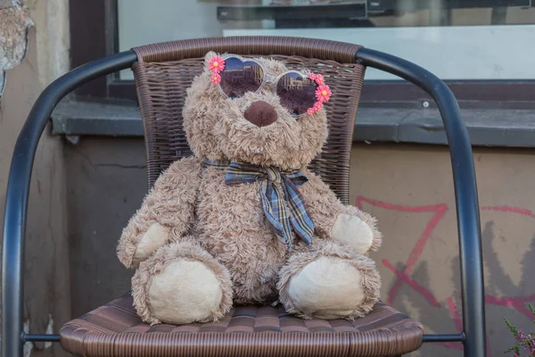 Ciudad Riga, Letonia. Un osito de peluche con gafas de sol sentado en un cha — Foto de Stock