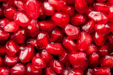 Siyah bir arka plan üzerinde olgunlaşmış sulu nar taneleri.