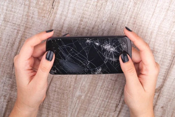 Смартфон со сломанным экраном в руке девушки — стоковое фото