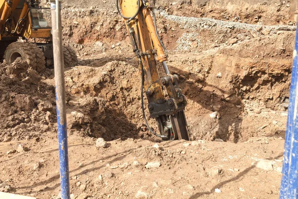 Excavator with a jackhammer breaks rocks in the ground — Stock Photo, Image
