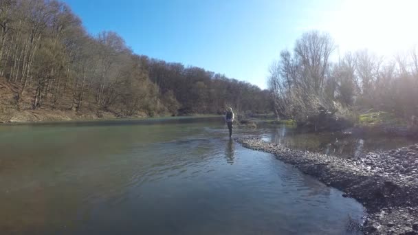 Una mujer atrapa un pez girando mientras está de pie en una orilla del río — Vídeos de Stock